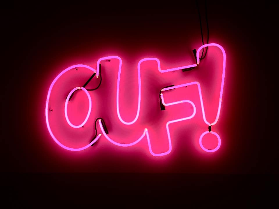 Un'insegna al neon rosa shocking su sfondo nero che dice "Ouf!", tipica espressione francese